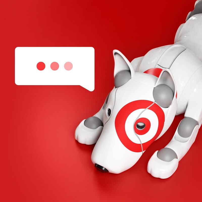 White robot dog with a red bullseye eye lies on a red background beside a speech bubble showing three typing dots.