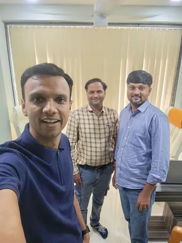 Selfie of Gaurav with two smiling men in a room with vertical blinds, reuniting after a long time.