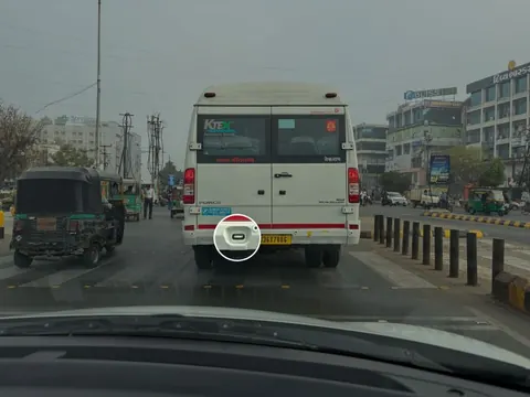 White van on a busy street, its rear door fitting circled for resembling an oversized USB-C port.