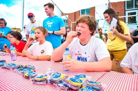 Kids eating MoonPies at an outdoor contest table covered with wrapped Chocolate Moon Pies and water bottles