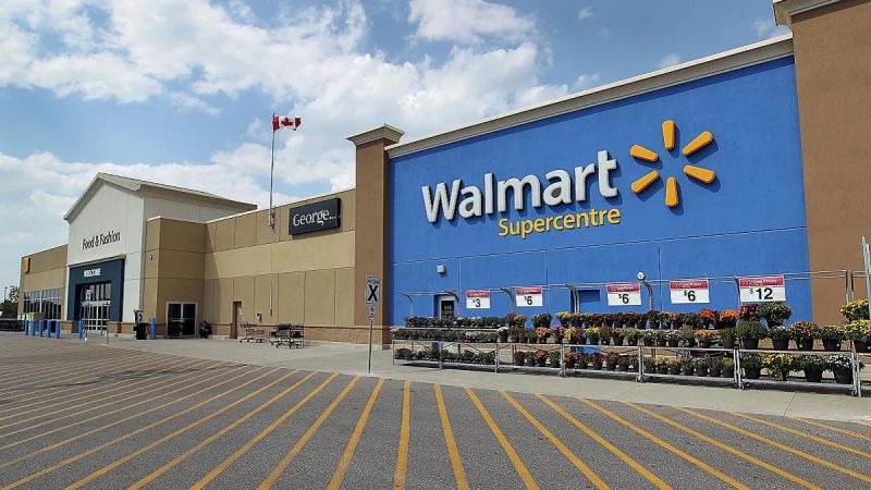Exterior of a Walmart Supercentre with flower displays and empty parking spaces under a partly cloudy sky