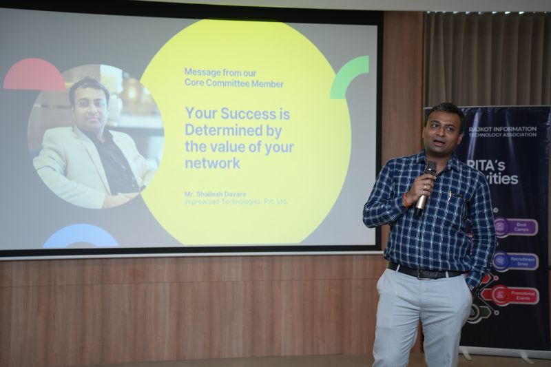 A man with a microphone stands beside a slide reading Your Success is Determined by the value of your network.