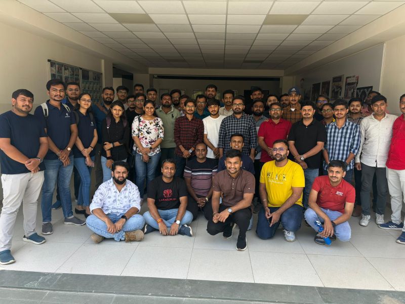A large group of meetup attendees poses together for a group photo in a building corridor.