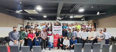 Group photo of dozens of attendees around an IT Sales Community Rajkot chapter meetup banner.
