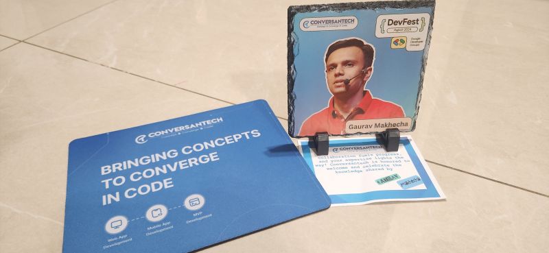 DevFest slate memento with Gaurav Makhecha's photo beside a Conversantech branded mousepad and card.