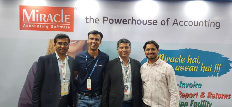Four men pose in front of a Miracle Accounting Software banner that reads 'the Powerhouse of Accounting'.