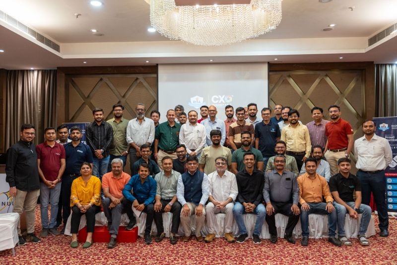 A large group of attendees poses for a photo in a banquet hall in front of a projector screen.
