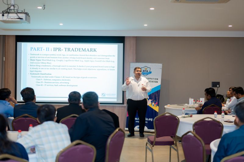 A presenter gestures beside a slide about trademarks and IPR classification at a seminar.