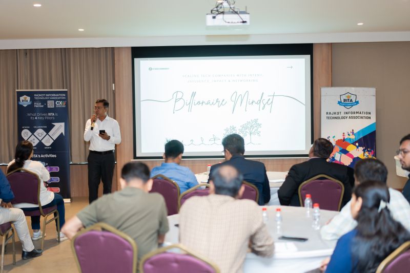 A man holding a microphone presents a slide titled Billionaire Mindset at a conference.