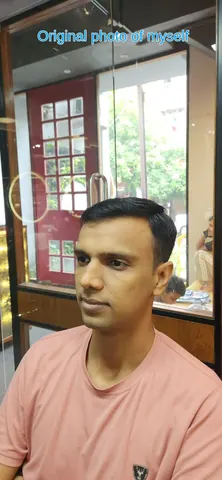 Gaurav in a pink t-shirt with short, neatly parted hair, seated indoors in front of a glass door with a red frame.