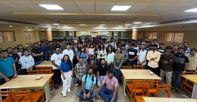 A large group of students and organizers pose together for a photo in an indoor hall after the session.
